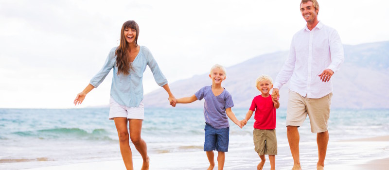 Man and Woman walking accross the beach with their 2 children