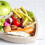 A Heart Shaped Bowl Filled With Vegetables With An Apple By The Side