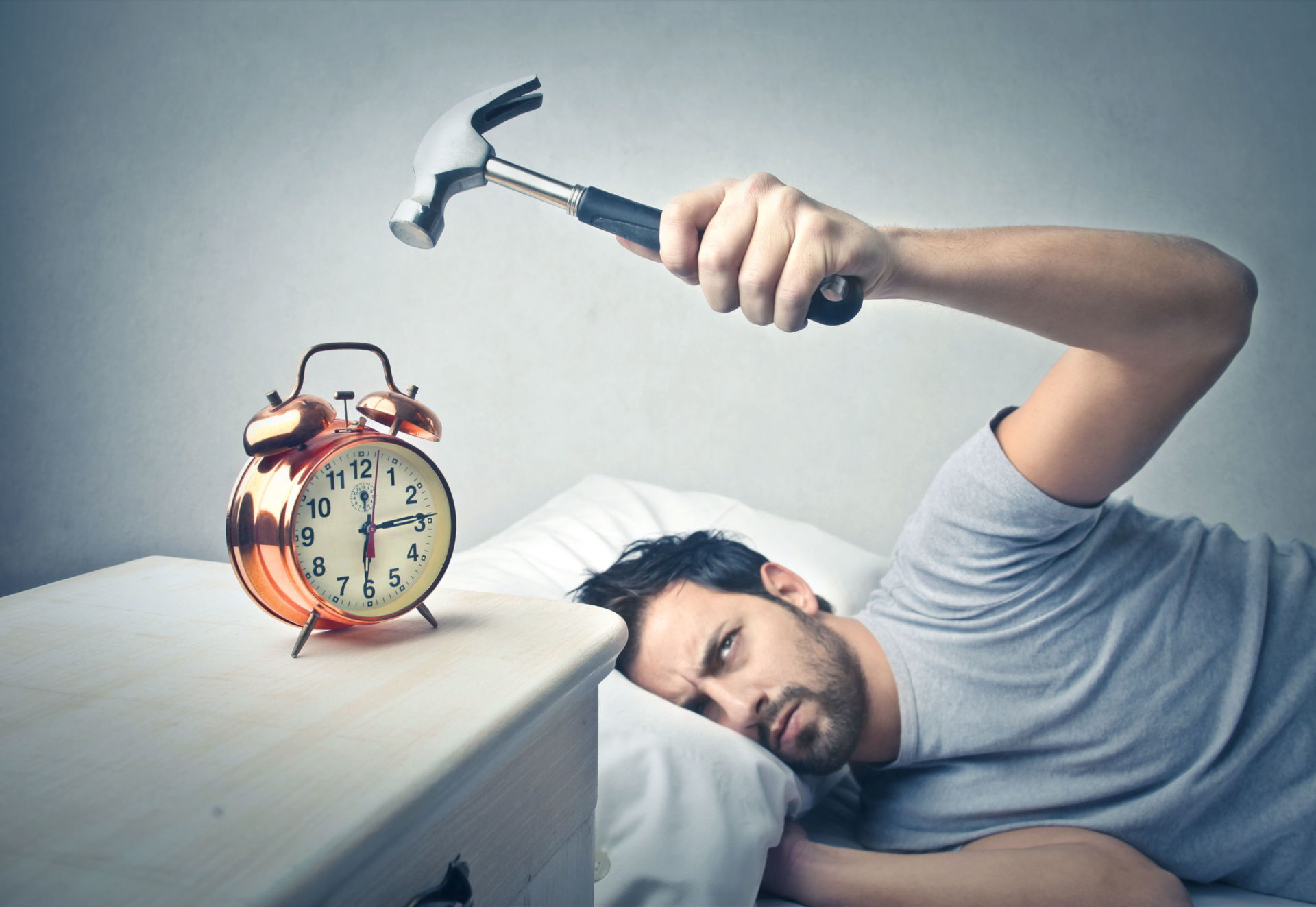 Man Hitting Alarm Clock With A Hammer As He Tries To Sleep