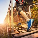 Man Walking Accross A Bridge With The Sun Shining In The Background