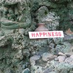 The Word Happiness Printed On White Background Among Some Grey Rocks Stones And Pottery