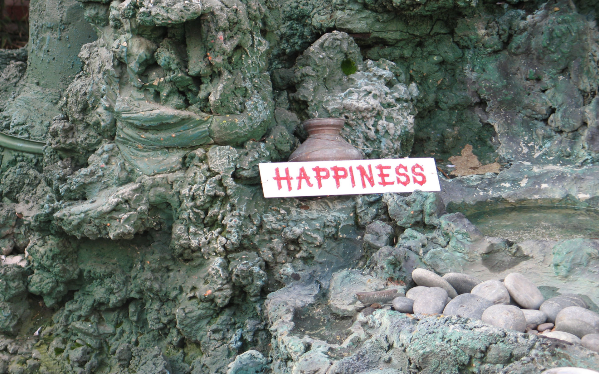 The Word Happiness Printed On White Background Among Some Grey Rocks Stones And Pottery