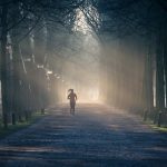 Woman Jogging Down A Dirt Road On A Winter Sunny Morning