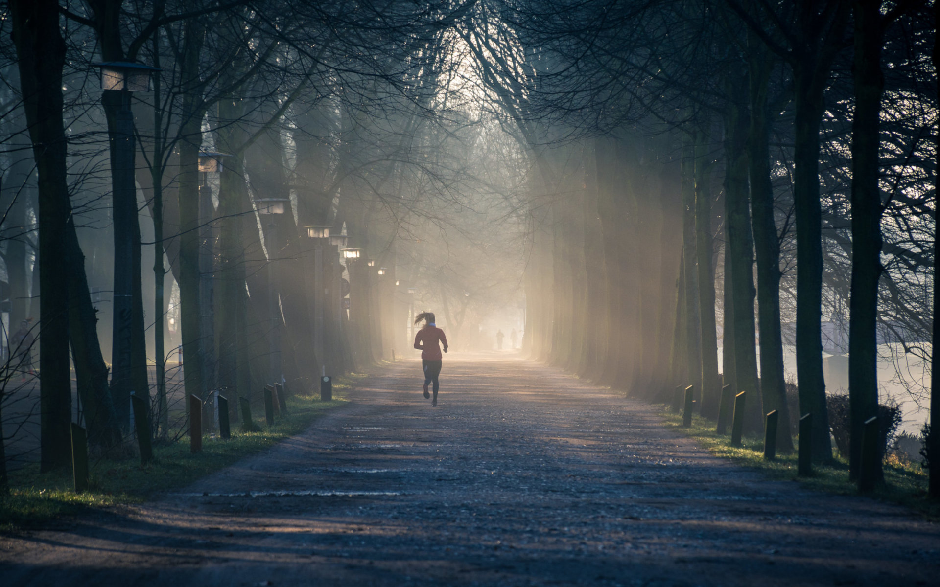 Woman Jogging Down A Dirt Road On A Winter Sunny Morning