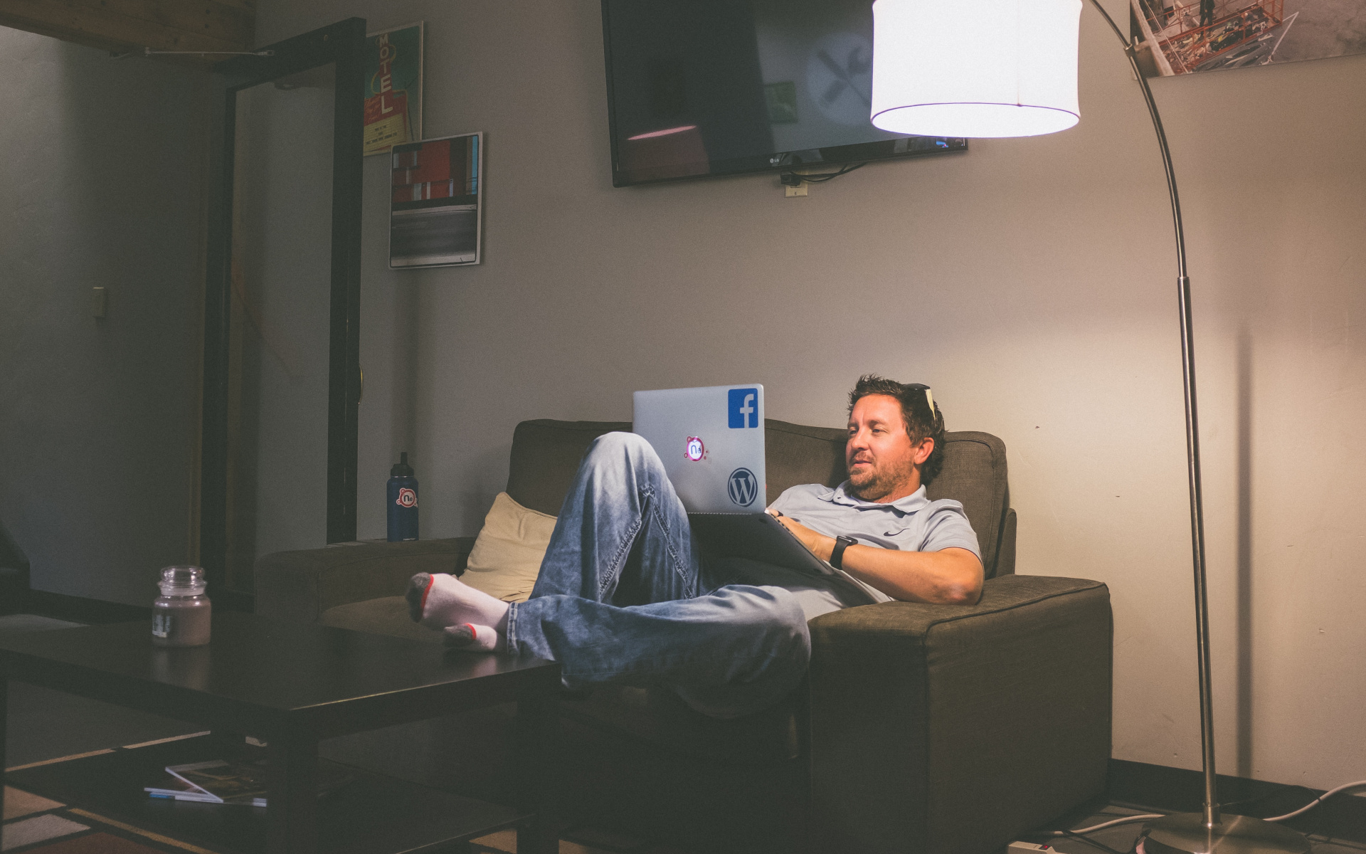 Man Sitting On Couch Looking At A Laptop