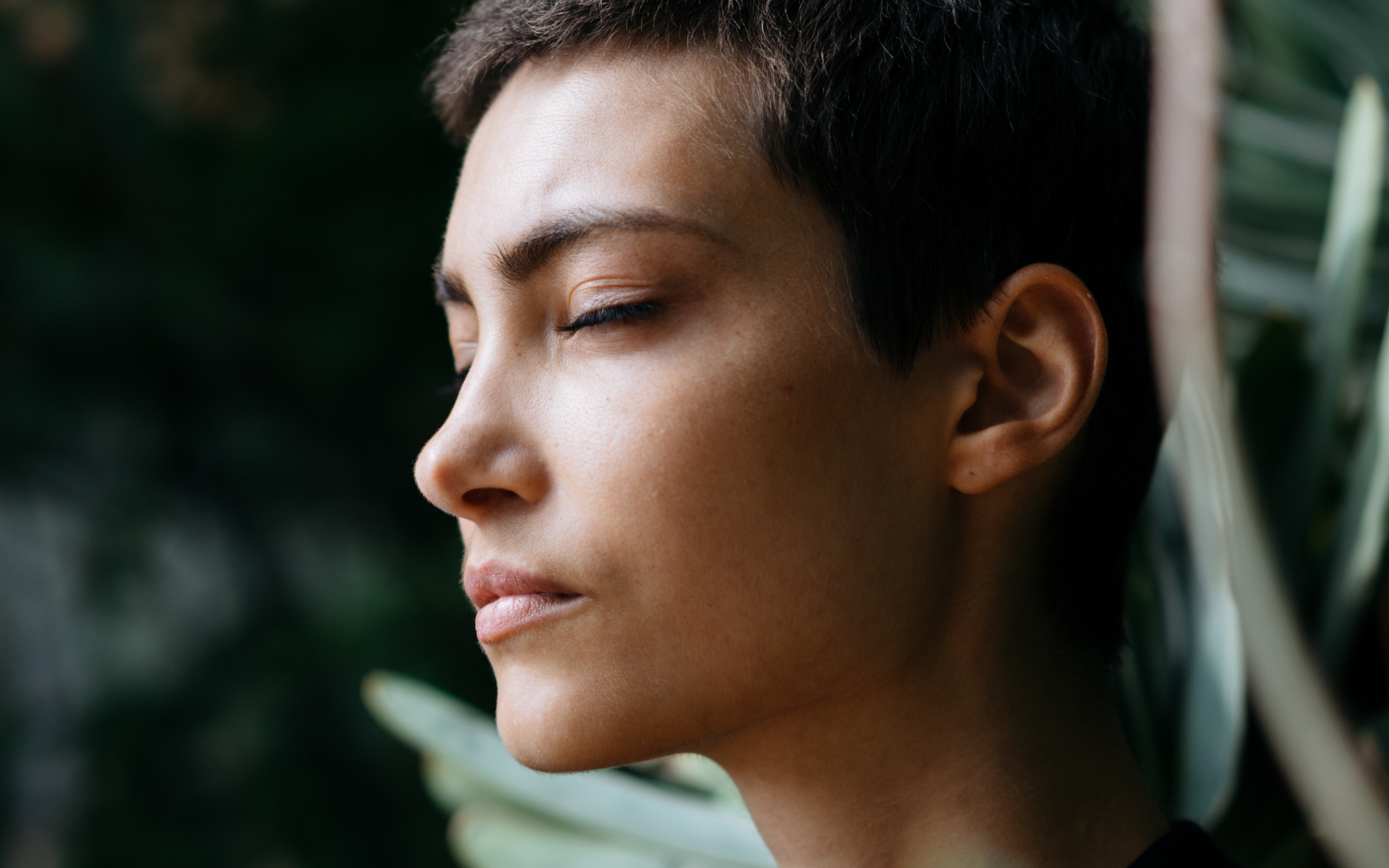 Woman In Front Of Green Tree With Her Eyes Closed In Deep Thought